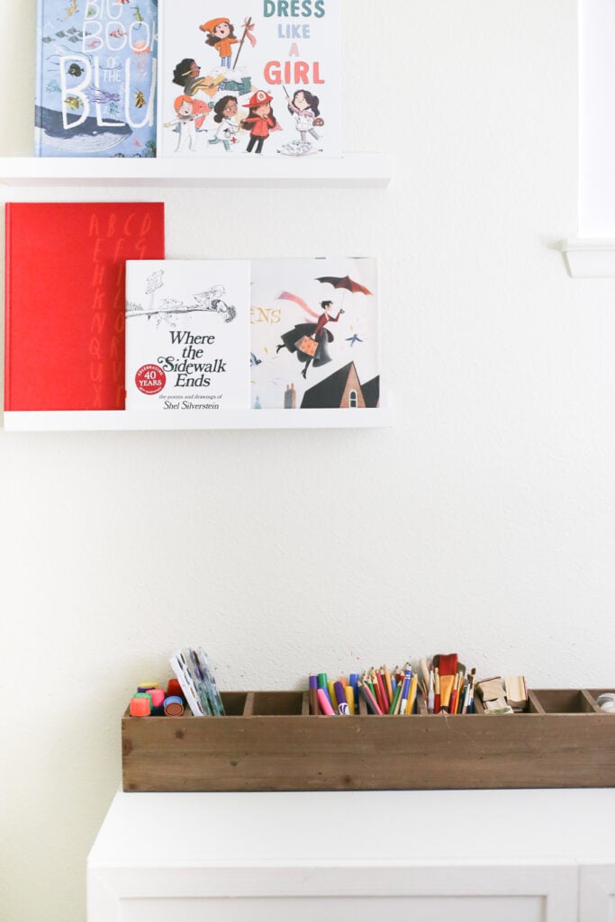 Art caddy and picture ledges for books in a kids playroom.