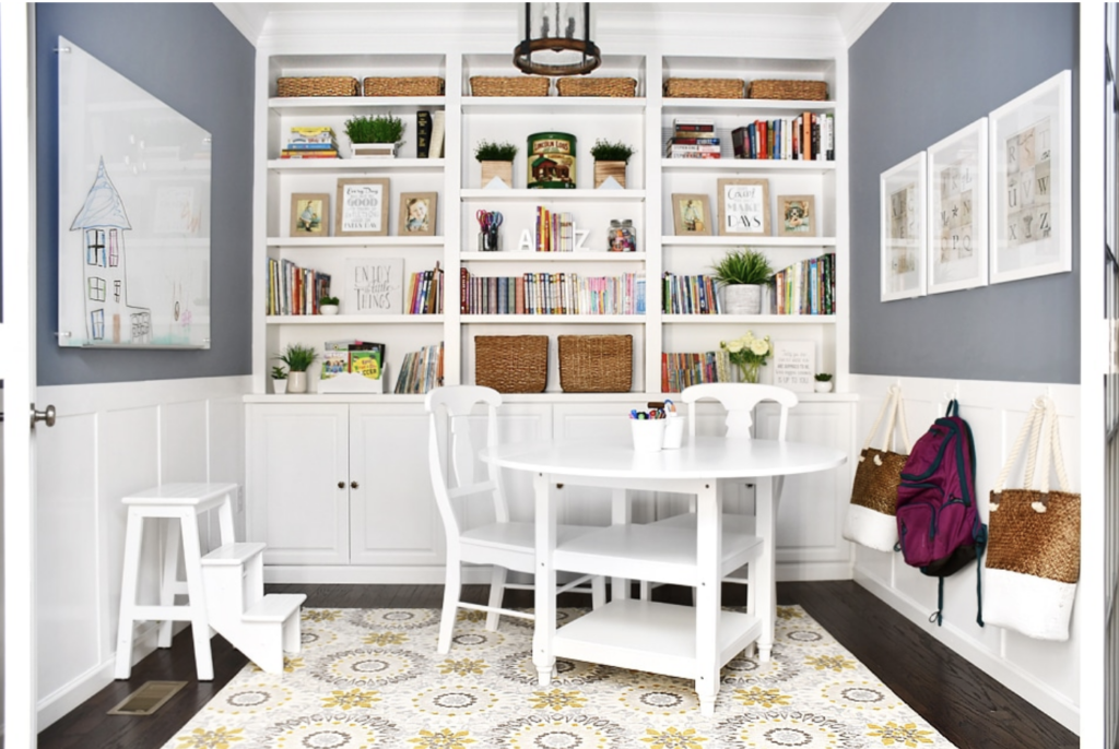 Home office with Sherwin Williams Storm Cloud and white built in bookshelves, white wainscotting, and a white table and chairs.