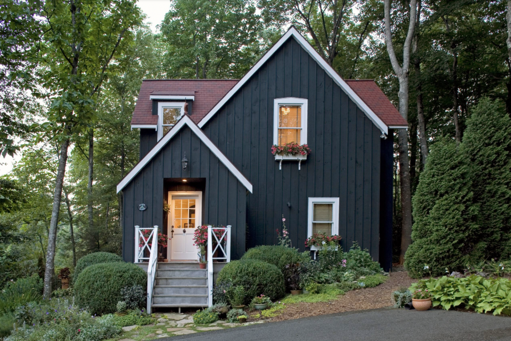 Modern black painted house cottage with lush green landscaping