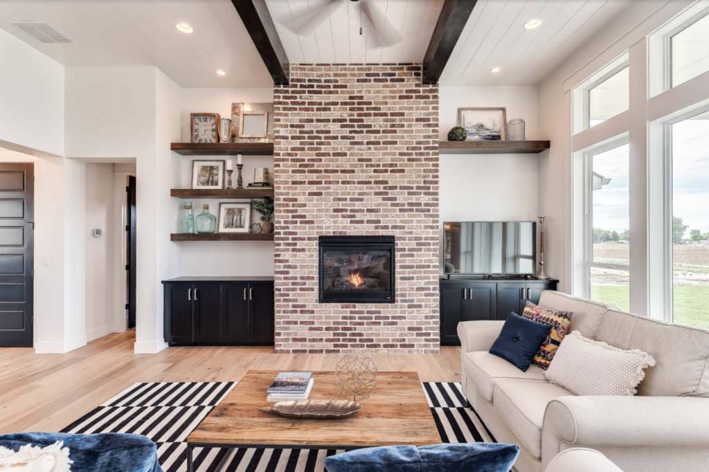 Light brick fireplace with dark floating shelves and dark cabinets in a bright living room.