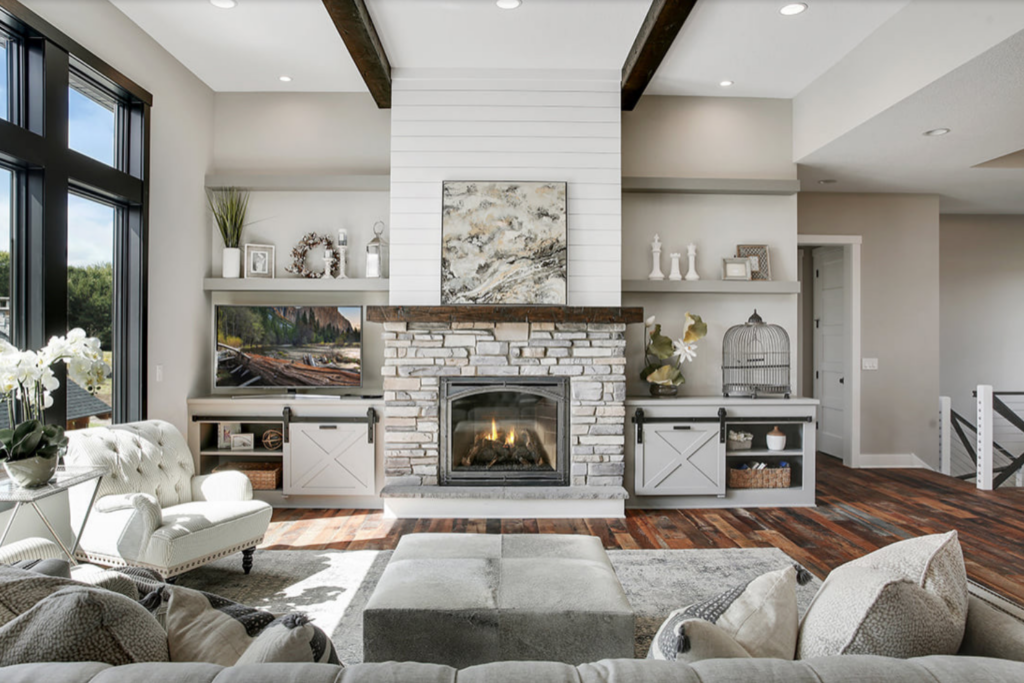 Natural stone fireplace with floating shelves in a farmhouse living room with dark wood flooring.