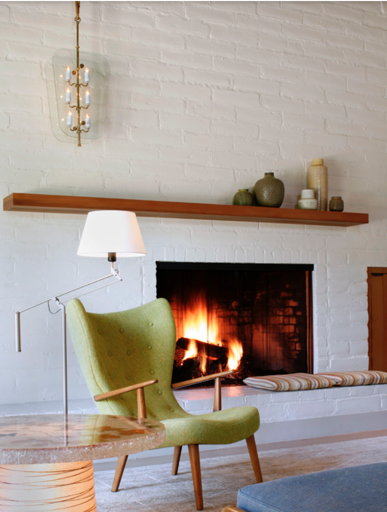 Long floating shelf around this fireplace that also acts as a mantle. The fireplace is made with white painted brick.