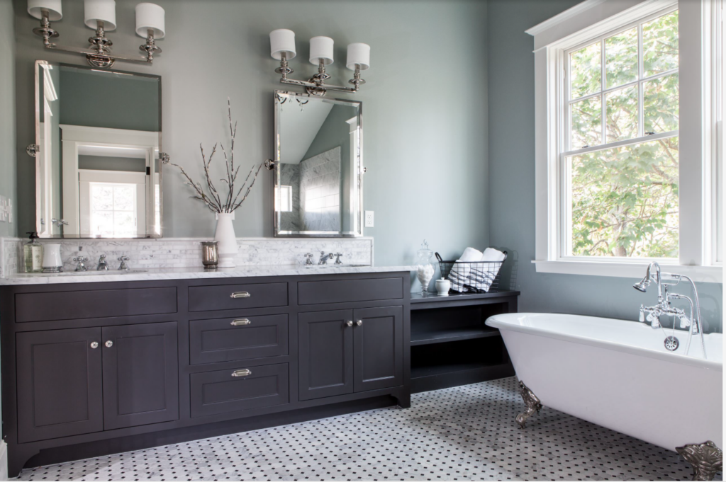 Bathroom cabinet painted a dark gray color in a large bathroom with tons of natural lighting and a stand alone tub.