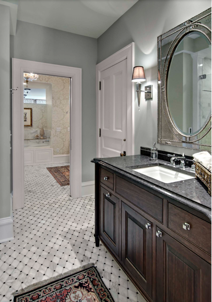 Dark wood bathroom vanity in a large bathroom with penny tile flooring and a marble countertop.