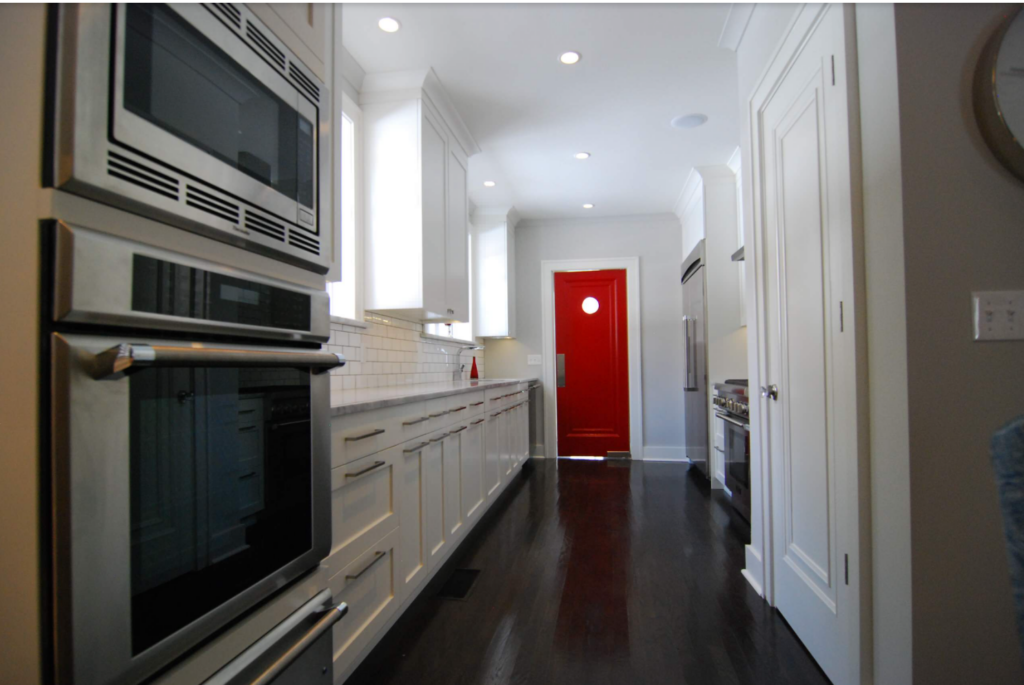 Bright red door in a small galley kitchen with dark features.