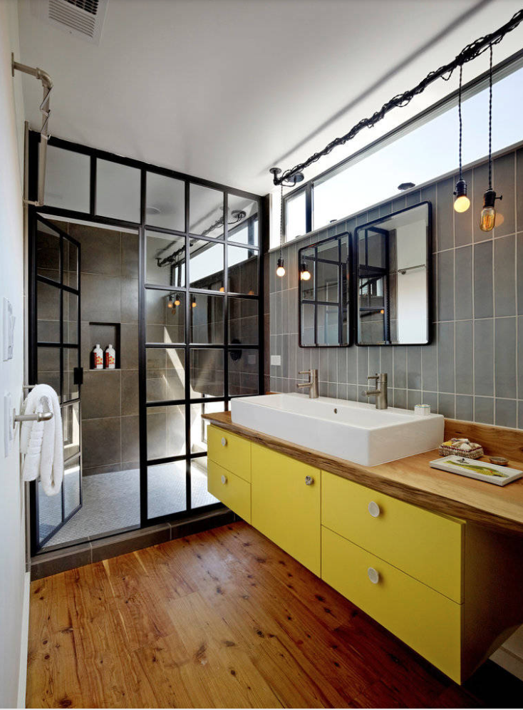 Bright yellow bathroom vanity in modern bathrom with wood flooring and wood countertops.